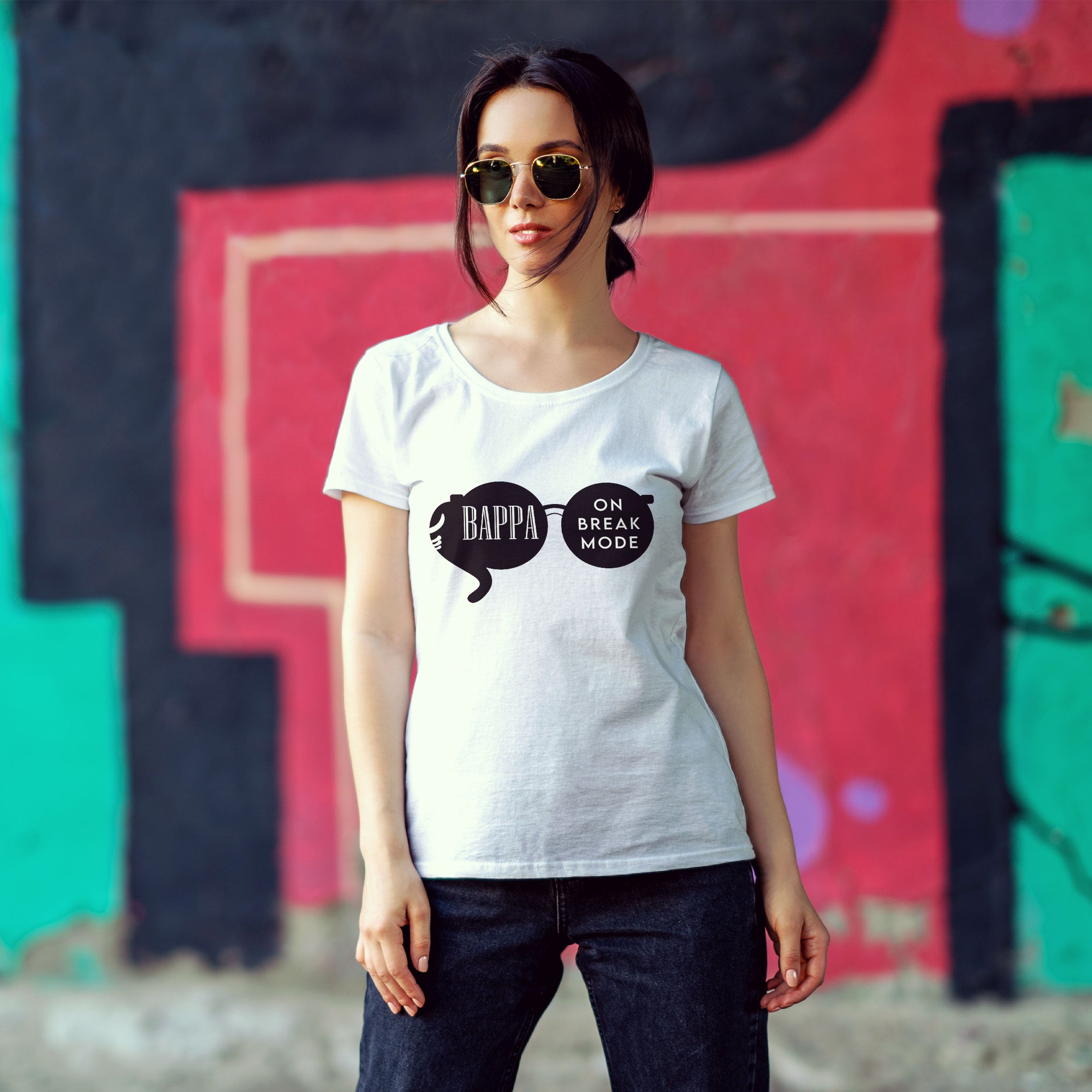 Woman wearing a white t-shirt with a graphic design in front of a colorful graffiti wall.