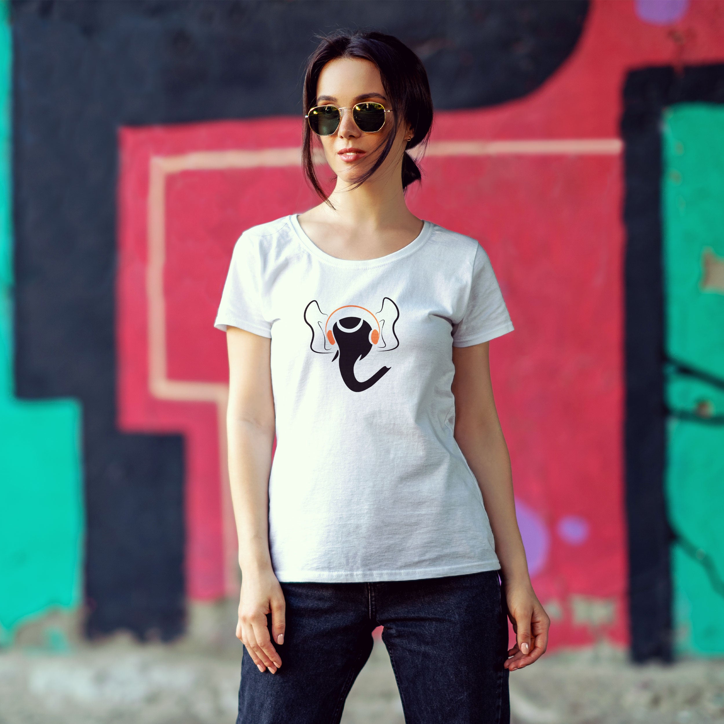 Woman wearing a white t-shirt with a graphic design in front of colorful graffiti.