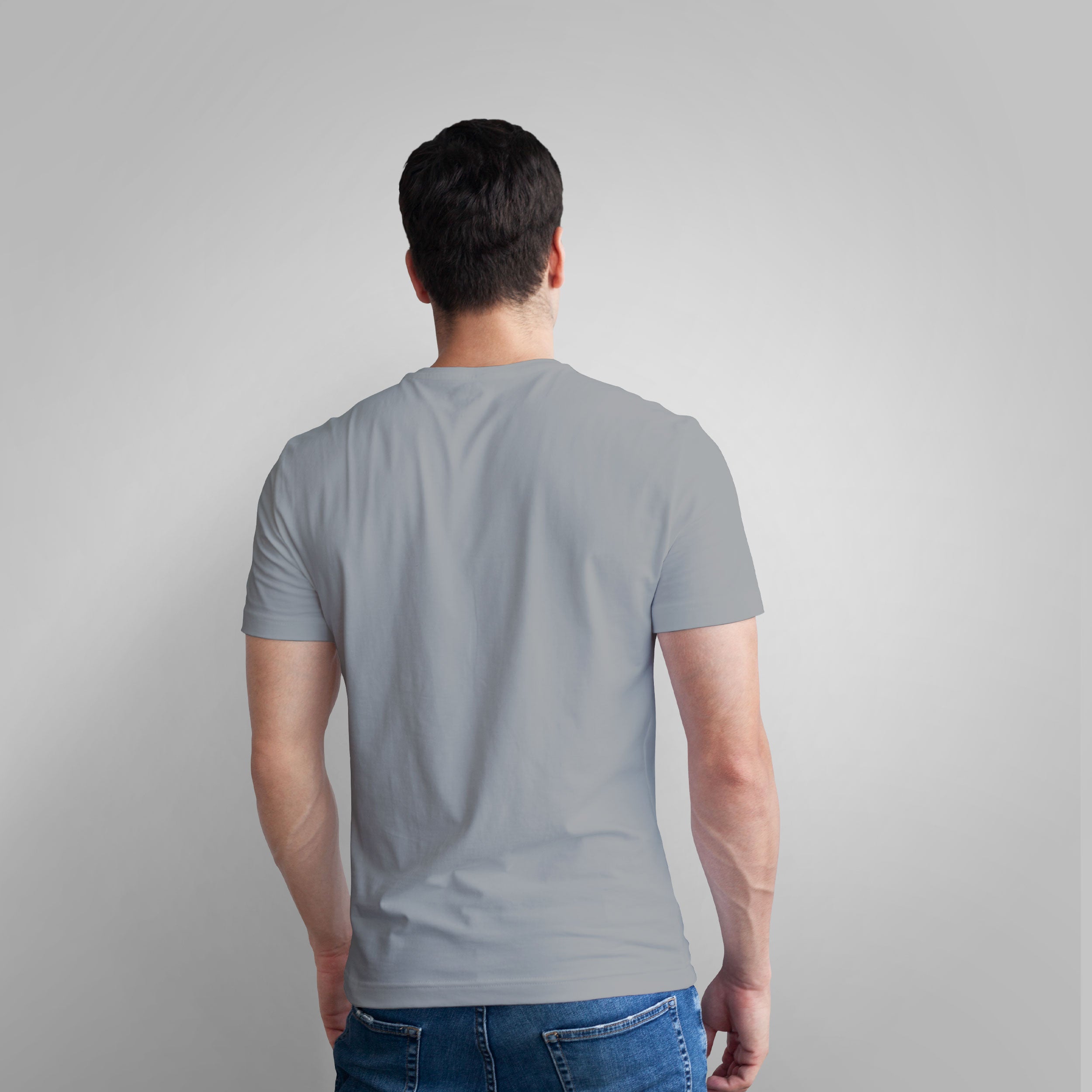 Man wearing a gray t-shirt with a graphic design on a plain background