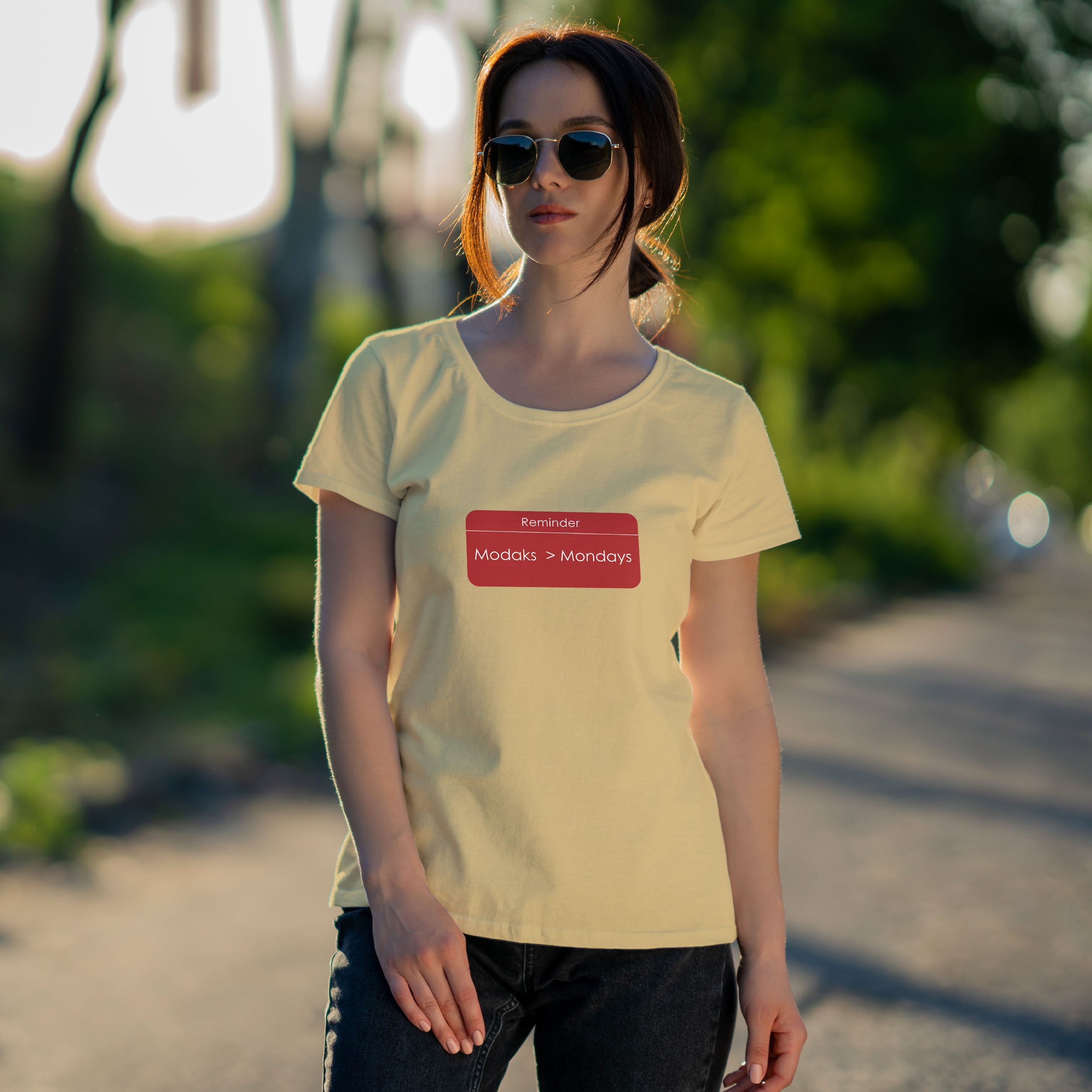 Woman wearing a beige t-shirt with a red graphic and sunglasses, standing in front of a colorful graffiti wall.
