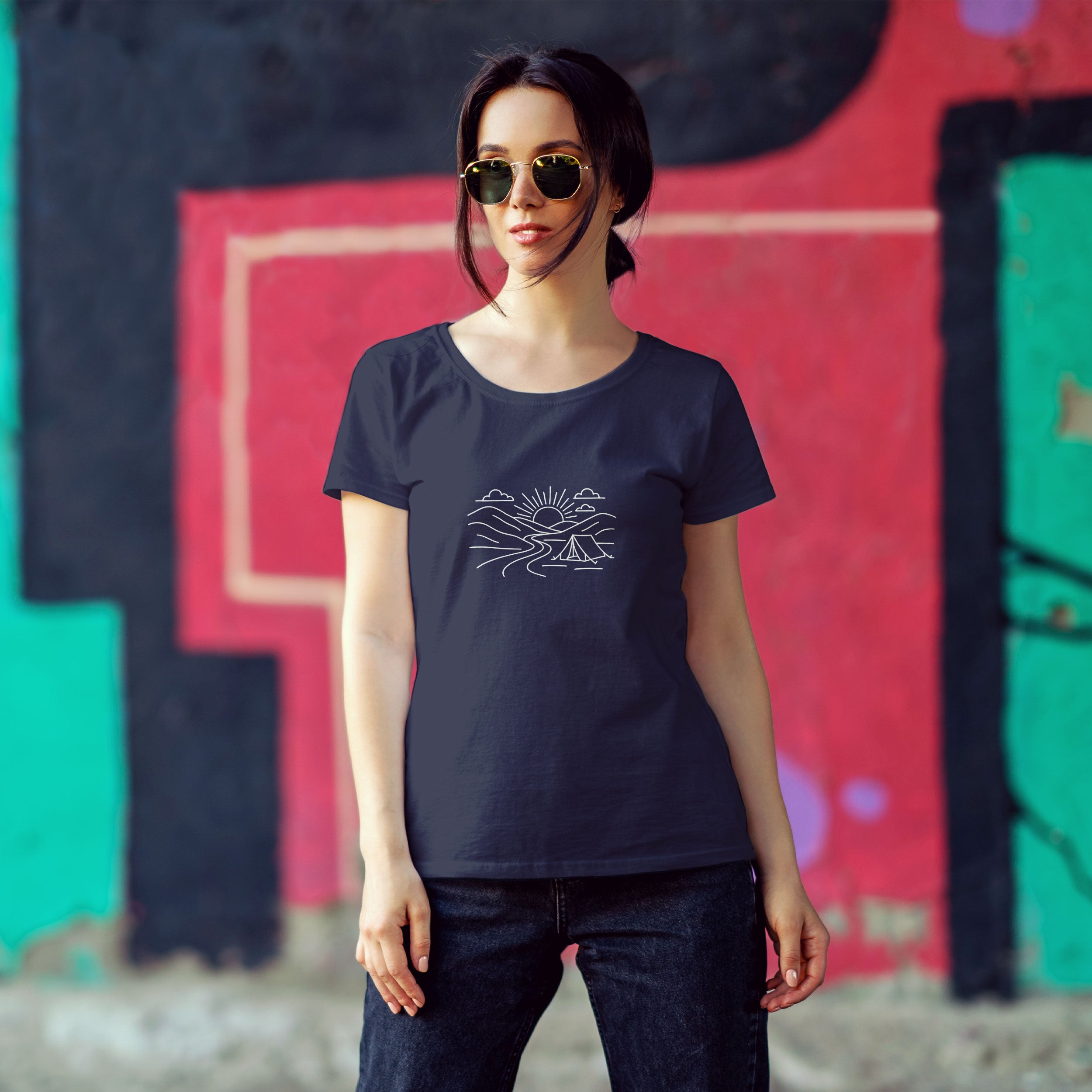 Woman wearing a navy blue t-shirt with a white graphic design against a colorful graffiti wall.