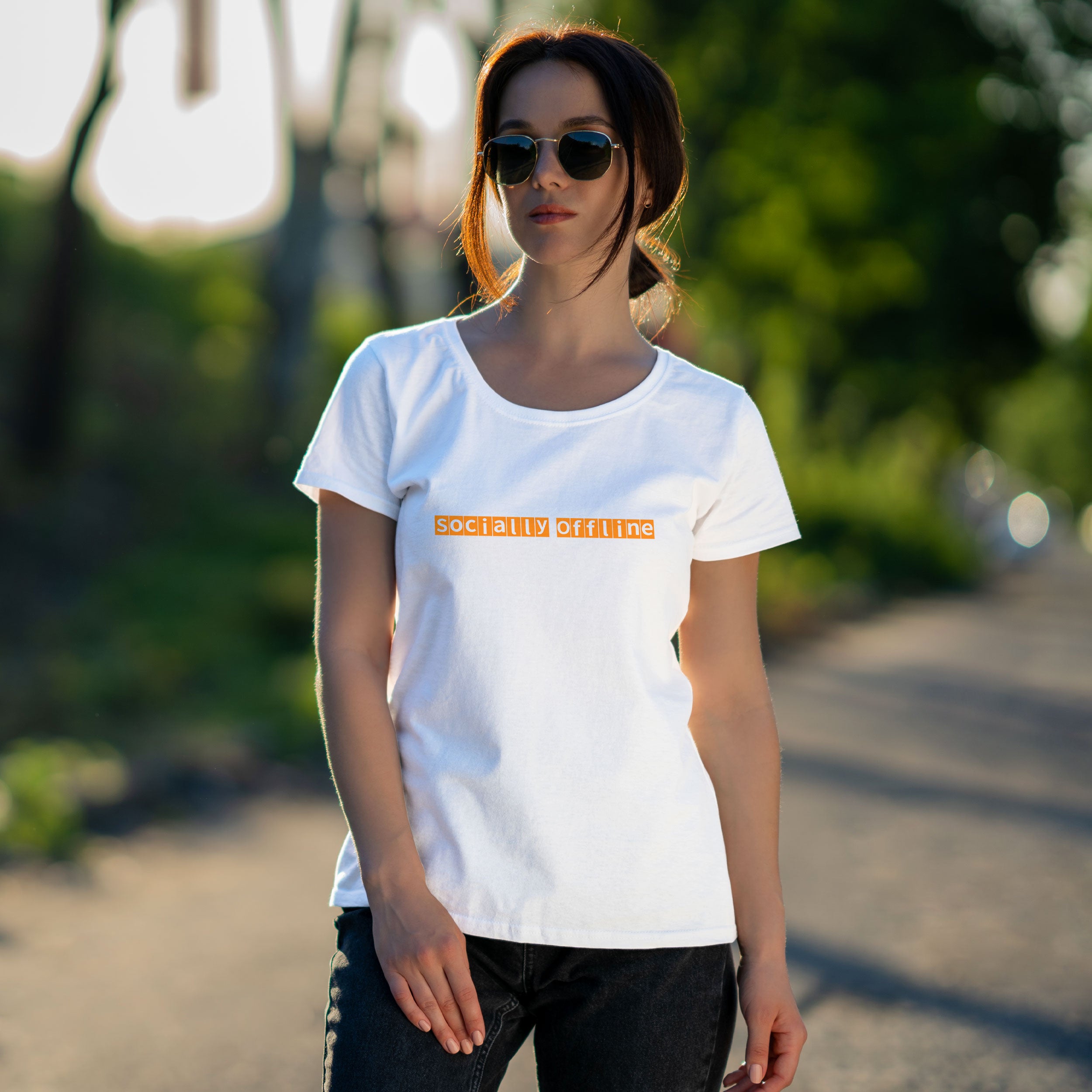 Woman wearing a white t-shirt with yellow text in front of a colorful graffiti wall.