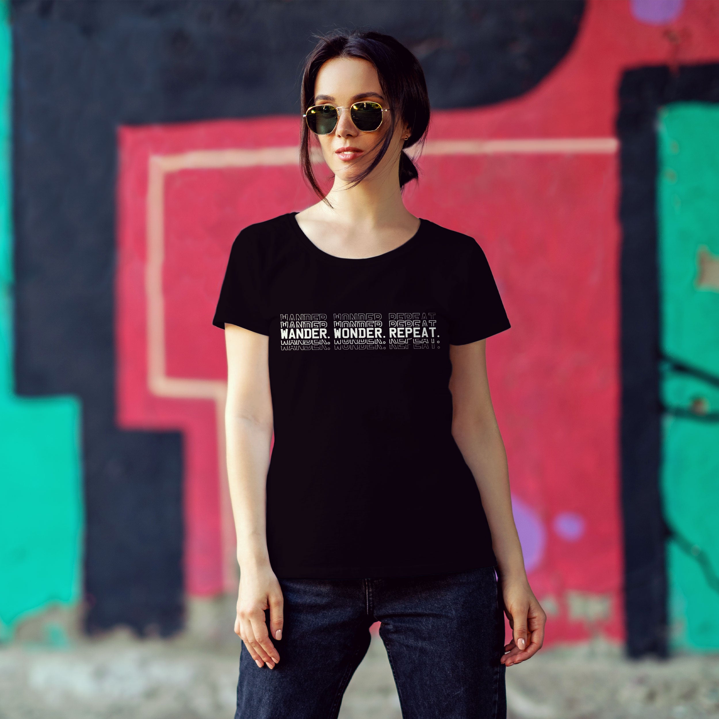 Woman wearing a black t-shirt with text in front of a colorful mural.